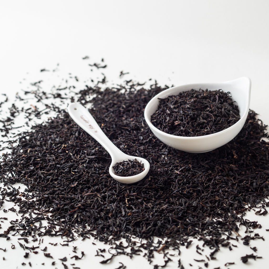 Loose Coconut Black Tea on white surface with decorative white teaspoon and bowl  - BESPOKE PROVISIONS